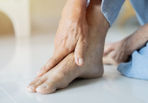 Cropped shot of an unrecognizable man suffering with foot cramp in the room. Selective focus, copy space.